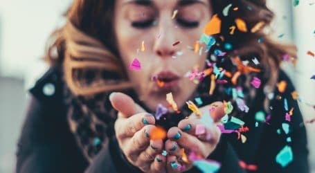 woman blowing paper strips in selective focus photography