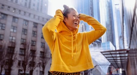 woman in yellow long sleeve shirt standing on building during daytime