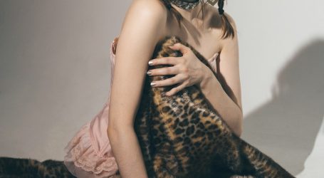 woman in brown and black leopard print sleeveless dress sitting on bed