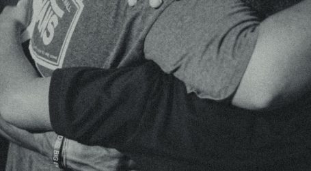 grayscale photography of men doing group hug