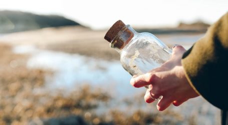 shallow focus photo of person holding clear glass bottle