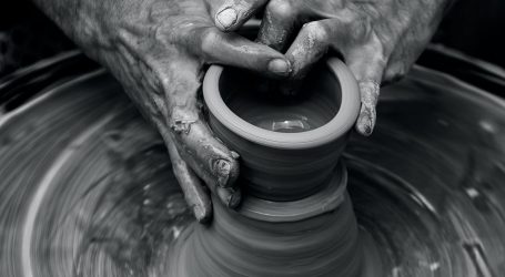 Messy hands sculpting on a pottery wheel in motion