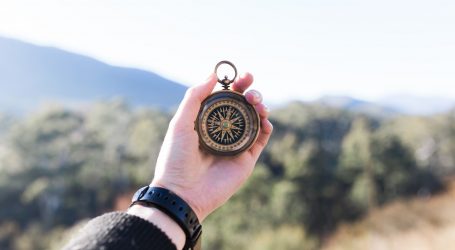 person holding compass selective focus photography