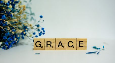 a wooden block that says grace next to a bouquet of flowers