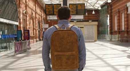 man in brown and black backpack standing on sidewalk during daytime