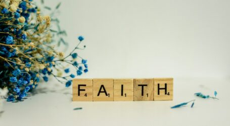 a wooden block that says faith next to blue flowers